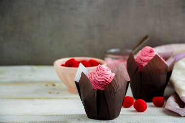 Pembe krem peynir ile dekore edilmiş cupcakes sırlı ve ahududu kapat