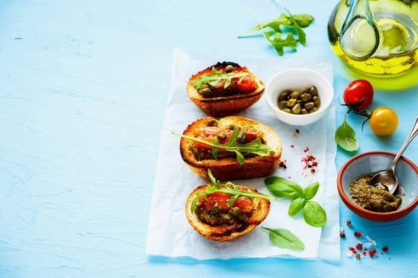 Close up of fresh smoked salmon toasts with arugula, pesto sauce and capers