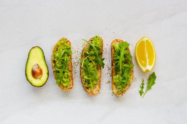 Roka ile avokado tost düz-lay. İyi yağları ham sağlıklı beslenme kavramı.