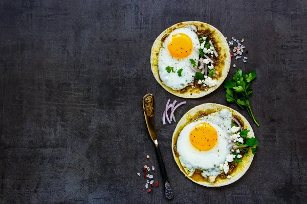 Corn tortillas, fried eggs, pesto sauce and feta cheese flat lay