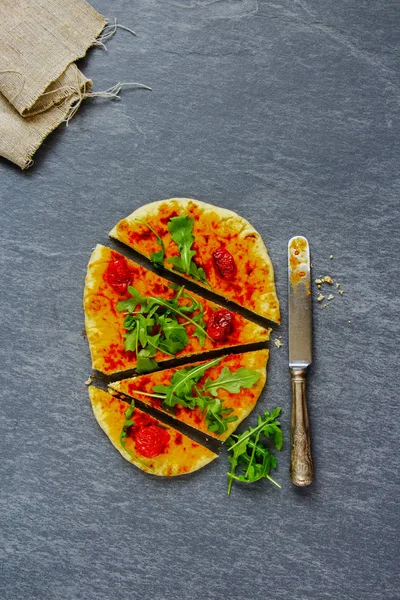 Flat-lay of freshly baked vegetarian pizza with arugula