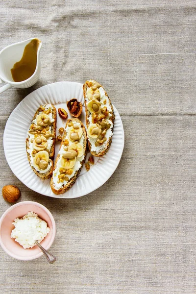 Toasts with ricotta cheese, banana and nuts flat lay