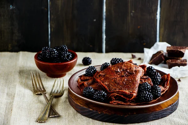 Homemade chocolate crepes, thin pancakes with fresh blackberries