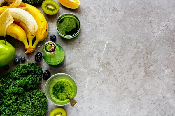 Making green smoothie. Flat lay of healthy ingredients for making detox smoothie drink over grey concrete background - Image