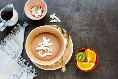 Düz-lay akçaağaç şurubu, taze meyve ve çikolata yoğurt kase ile Hindistan cevizi cips, üstten görünüm. Tatlı kahvaltı beton zemin üzerine - resim