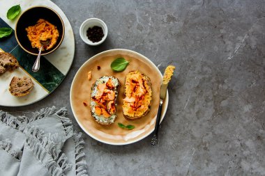 Sağlıklı somon füme gri beton tablo arka planı düz koymak üzerinde yumuşak keçi peyniri ve fesleğen ile kızartır. Üstten Görünüm - görüntü
