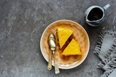 Düz-lay gri arka plan, üstten görünüm üzerinde akçaağaç şurubu ile yumuşak ev yapımı peynir pasta.