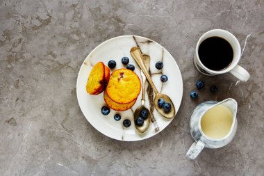Düz-lay ile taze yaban mersini taze pişmiş böğürtlenli kek. Kahve, süt gri beton tablo arka plan üzerinde şişe ile Servis Kahvaltı. Üstten Görünüm, uzay - görüntü