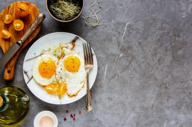 Düz lezzetli breakfast gri beton tablo arka plan üzerinde yatıyordu. Kızarmış yumurta, mikro Yeşiller, plaka, üstten görünüm taze domates. Temiz beslenme, diyet, vejetaryen yemek - görüntü