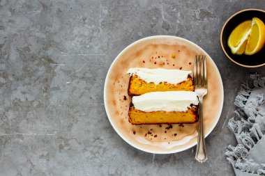 Düz dilimlenmiş limon pasta tatlı mascarpone tabak içinde krem ile beton gri arka plan üstten görünüm - görüntü üzerinde göklere