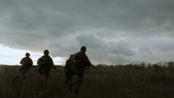 Silhouettes de soldats courant à travers le champ — Video