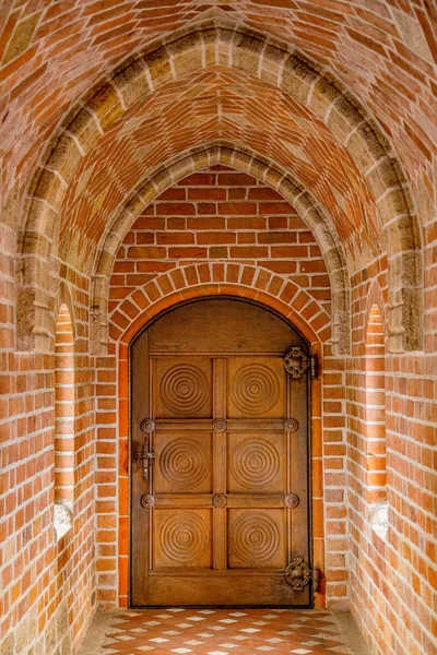 Wooden door in a brick tunnel, close up