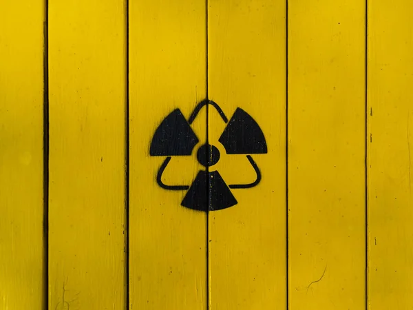 A sugárzás jele sárga fából készült táblán. — Stock Fotó
