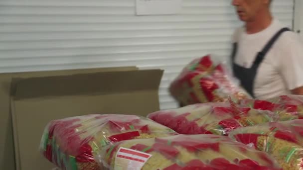 Trabajador apilando bolsas de fideos en un contenedor de plástico — Vídeos de Stock