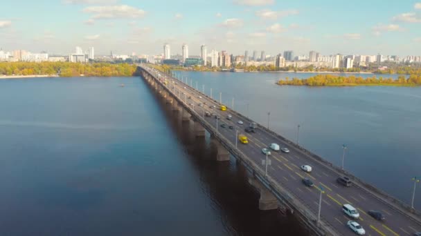 Движение по мосту через широкую реку осенью . — стоковое видео