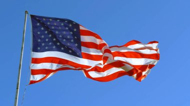Güneşli bir günde Amerikan bayrağı rüzgarda dalgalanıyor. Amenrika ulusal bayramının sembolü. Bağımsızlık Günü - Amerikan konsepti. Amerika Birleşik Devletleri 'nin ünlü bayrağını sallayarak.
