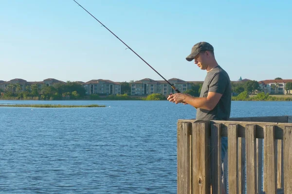 Fisherman cast fishing rod in lake or river water.