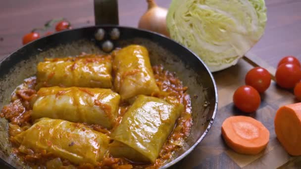 Tomatensaus kookt in een pan met koolrolletjes. — Stockvideo