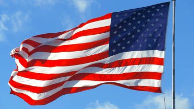 Mavi gökyüzü ve beyaz bulut önünde dalgalanan büyük Amerikan bayrağına yakın durun. Rüzgarda dalgalanan Amerikan Bayrağı. Birleşik Devletler bayrağını kapatın. Mavi Gök Altında Bulutlu Amerikan Bayrağı Dalgalanıyor.