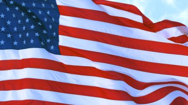 Güneşli bir günde açık mavi gökyüzüne karşı Amerikan bayrağı dalgalanır. Kapat..
