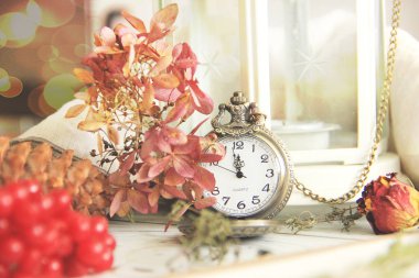 Sonbahar natürmort bir saatli sonbahar çiçekler, kırmızı meyve ve yaprakları