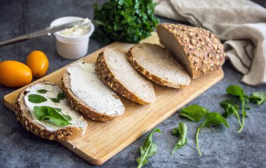 Mutfak arka plan - bir ahşap tahta, yumuşak peynir ve Yeşiller dilim tam tahıllı ekmek