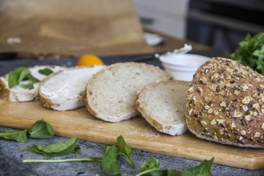 Mutfak arka plan - bir ahşap tahta, yumuşak peynir ve Yeşiller dilim tam tahıllı ekmek