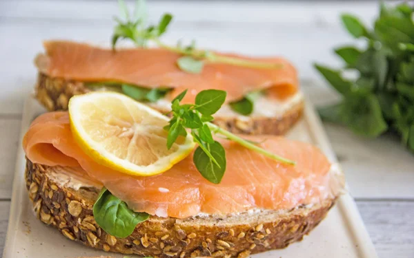Sandviç somon ve ahşap arka plan üzerinde limon ile