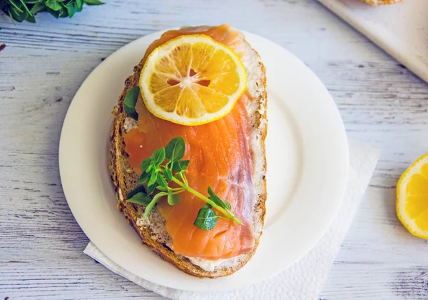 Sandviç somon ve ahşap arka plan üzerinde limon ile