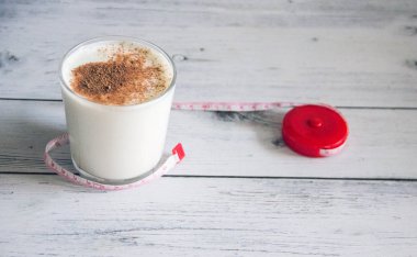 Kefir ile tarçın bir cam ve hafif ahşap arka plan üzerinde bir ölçüm bandı zayıflama