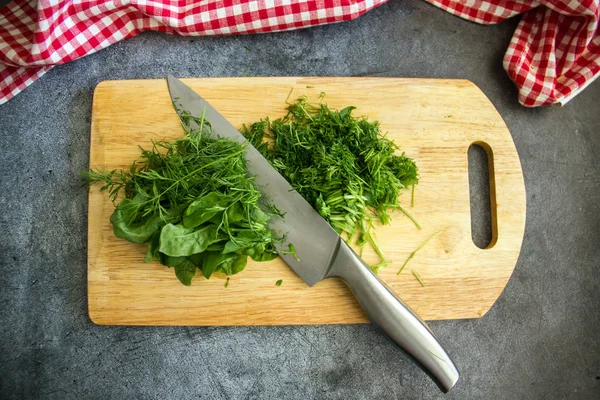 Bir beyaz tahta üzerinde kıyılmış taze yeşillik. Bir bıçak ve bir kafes içinde bir havlu içinde belgili tanımlık fotoğraf var..
