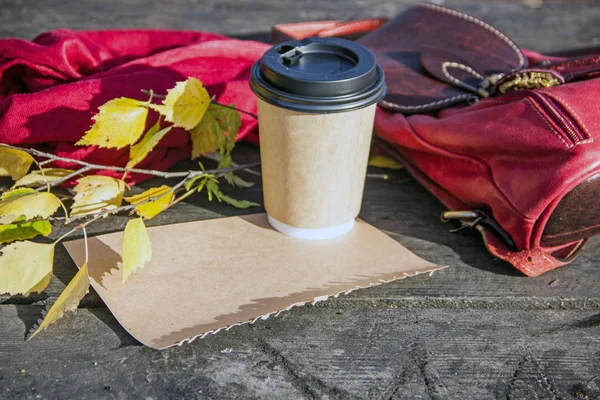 Ahşap bir arka plan üzerinde bardak kahve, eldiven ve sonbahar yaprakları