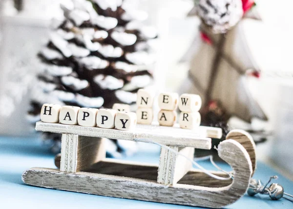 Noel arka plan - ahşap kızak, ağaç, koniler, oyuncak ve beyaz küpleri siyah harflerle 