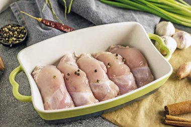 Ham ücretsiz aralığı kemiksiz derisiz tavuk uyluk bir pişirme çanağı içinde baharatlar ile