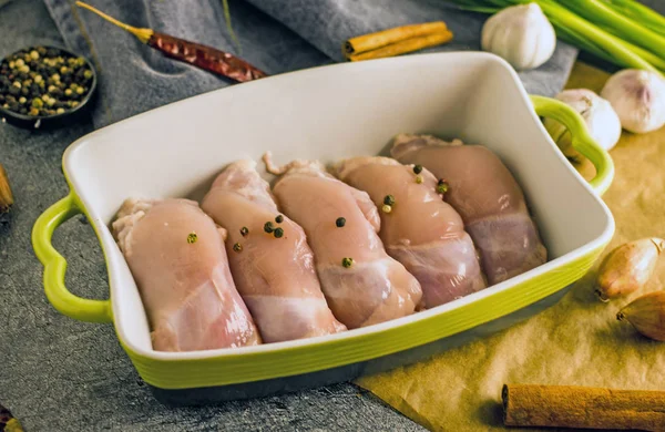 Ham ücretsiz aralığı kemiksiz derisiz tavuk uyluk bir pişirme çanağı içinde baharatlar ile