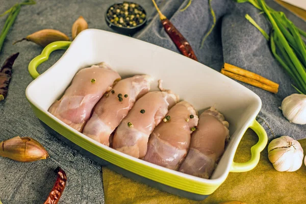 Ham ücretsiz aralığı kemiksiz derisiz tavuk uyluk bir pişirme çanağı içinde baharatlar ile