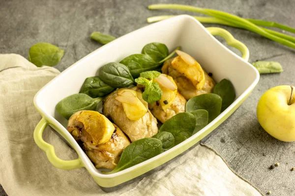 Bir pişirme çanağı ile karanlık bir taş zemin üzerine yeşil elma ile kızarmış tavuk dilim