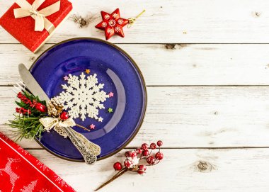 Noel tablo ayarı - tabak, çatal bıçak takımı ve hafif ahşap masa üzerinde Noel süsleri. Üstten görünüm.