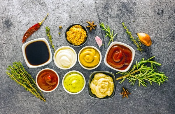 Soslar karanlık bir taş zemin üzerine kümesi. Mayonez, ketçap, soya sosu, hardal, peynir sos, baharat. Yukarıdan görüntülemek