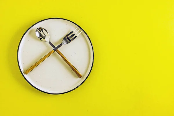 Boş tabak çatal kaşık ve çatalı sarı arka plan yakın çekim. Yukarıdan görüntüleyin. Mutfak arka plan