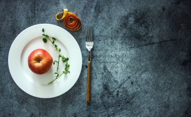 Teyp ve çatal bıçak takımı, bir arka plan hakkında diyetler, kilo, vejetaryenlik Tema hakkında arka plan ölçme yanında beyaz bir plaka üzerinde bir elma