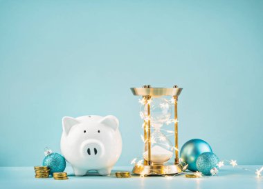 Kumbara ve rustik kum saati ışıklar mavi bir arka plan üzerinde sarılı. Sezon kavramı veren Noel armağan için kaydetmek için geri sayım.