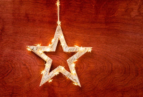 Rustic Christmas star decoration wrapped in lights on a beautiful red stained wood background