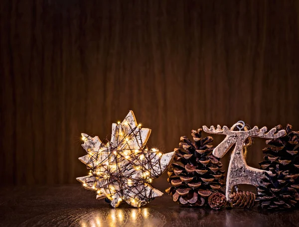 自然的圣诞装饰与质朴的枫叶装饰在黑暗的木材背景的灯光包裹 — 图库照片