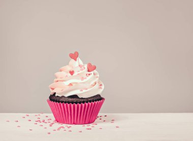 Sevgililer günü Cupcake tedavi buttercream buzlanma ve kalp ile gri bir arka plan üzerinde sprinkles