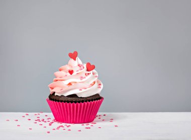 Sevgililer günü Cupcake tedavi buttercream buzlanma ve kalp ile gri bir arka plan üzerinde sprinkles