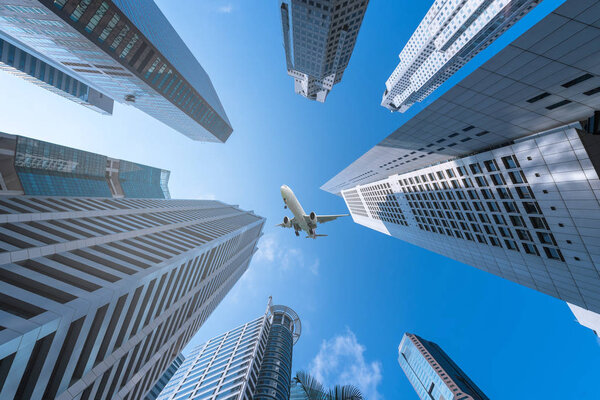 Plane flying over city on blue sky background.