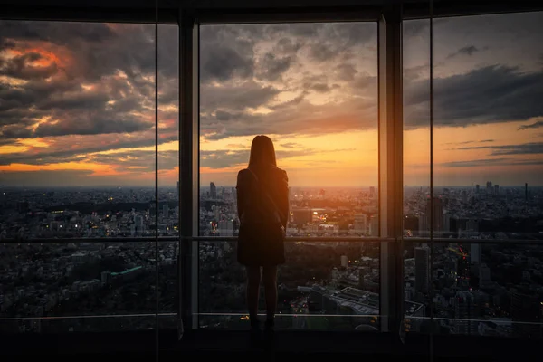 Tokyo siluetinin ve gökdelenler görünümünü gözlem güverte Japonya'da batımını Traveler kadın arkadan görünüş.