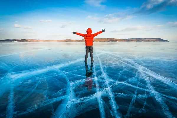 Hombre viajero usar ropa roja y levantar el brazo de pie sobre hielo de ruptura natural en agua helada en el lago Baikal, Siberia, Rusia . — Foto de Stock