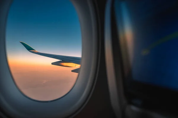 Ala de silueta de un avión al amanecer vista a través de la ventana . —  Fotos de Stock